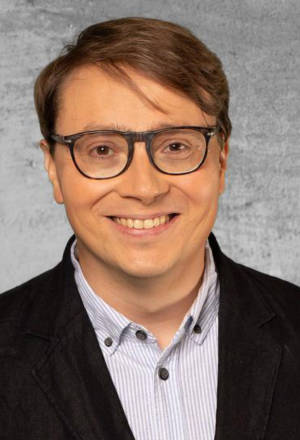 Hymyilevä ja silmälasipäinen Mikko Järvinen. Vihreä ympyrä, jossa teksti EER 2022 Uusimaa.