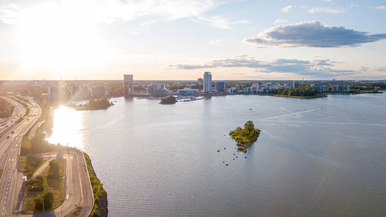 Ilmakuva, jossa vasemmalla autotie, takana taloja Espoon Keilaniemessä ja etualalla merta.