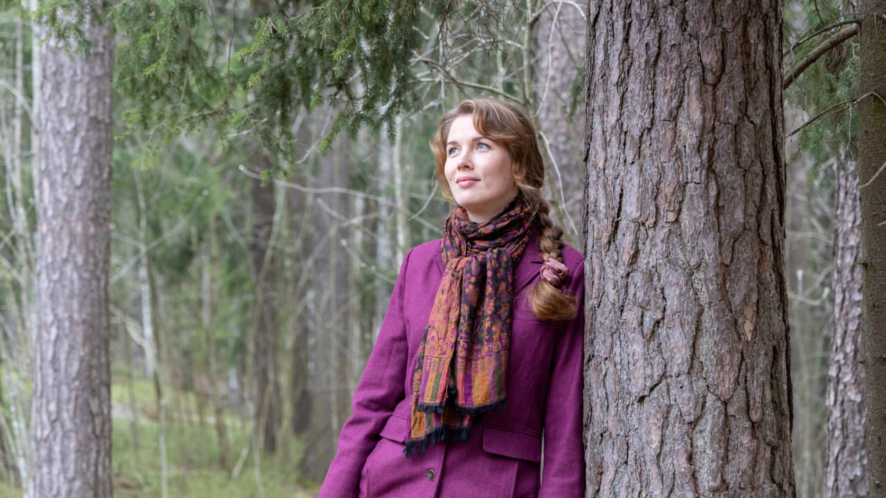 Maria Sirviö metsässä violetti takki yllään.